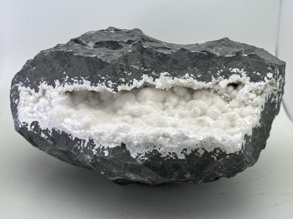 LARGE Okenite Geode Cottony Crystals: Okenite Geode. Okenite is a rare, soft silicate mineral known for its delicate, fibrous, cotton-like appearance. It often forms as white or colorless tufts of fine crystals that resemble soft,