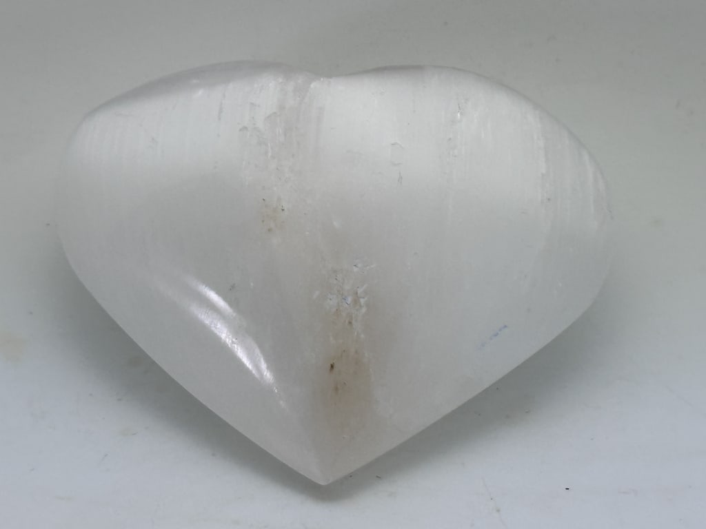 164.55 gram Selenite Carved Heart: Selenite is a mostly clear, transparent variety of the sulfate mineral gypsum. The name selenite is also commonly used for other varieties of gypsum, including satin spar gypsum, desert roses, and