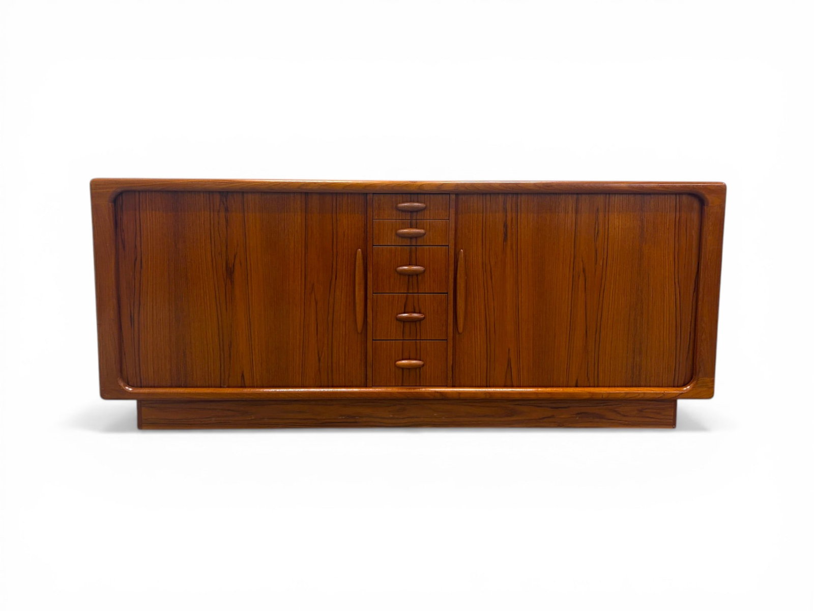 Dyrlund Tambour Door Sideboard: Dyrlund Danish modern teak sideboard. 2 tambour doors with a shelf and 5 drawers on the interior, 5 central drawers. Dyrlund label to the interior of top drawer. Dimensions: H: 30.625" W: 74.25" D: 19
