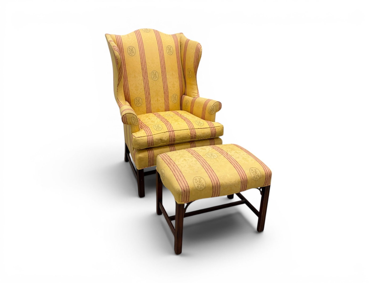 Upholstered Wing Chair & Ottoman: Wing chair and ottoman, matching yellow and pink striped upholstery with floral motif. Chair dimensions: H: 47" W: 33.5" D: 32", seat height 20" Ottoman dimensions: H: 18.75" W: 25" D: 19"