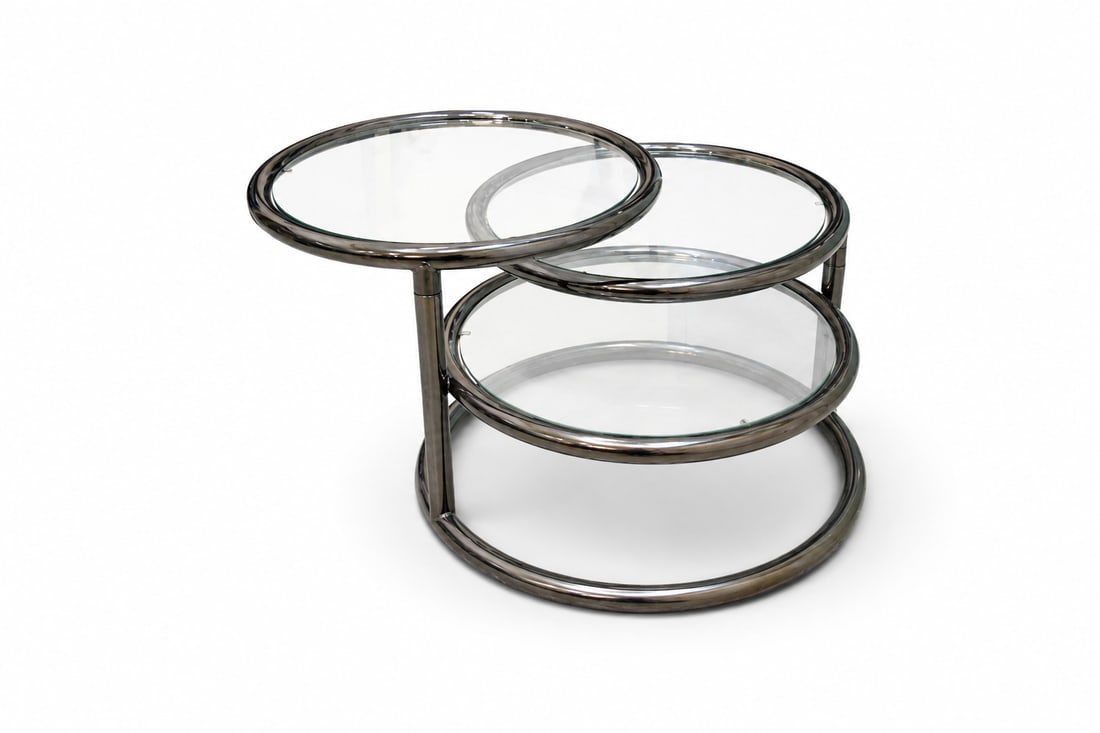Baughman Style 3 Tier Chrome & Glass Coffee Table: Chrome and glass 3 tier coffee table, in the style of Milo Baughman. Top 2 tiers swivel open and expand. Unsigned. Smallest dimensions: H: 16" W: 24" D: 22" Largest dimensions: H: 16" W: 66" D: 22"