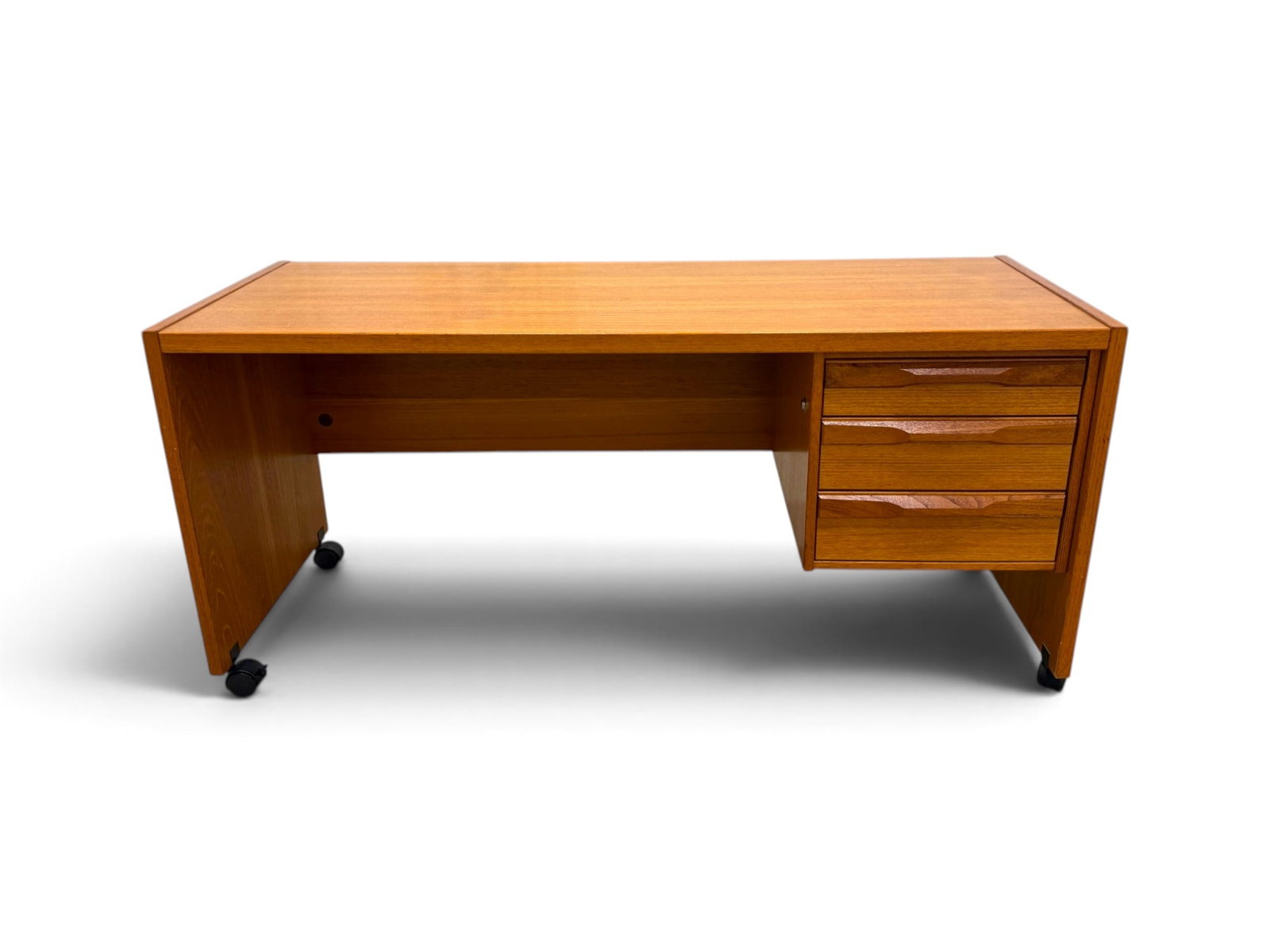 Danish Modern Teak Desk on Casters: A Danish Modern Teak Desk on Casters with three drawers. Marked 'Made in Denmark'Disassembles for easy transport. H:26.5" W:57.5" D:20"