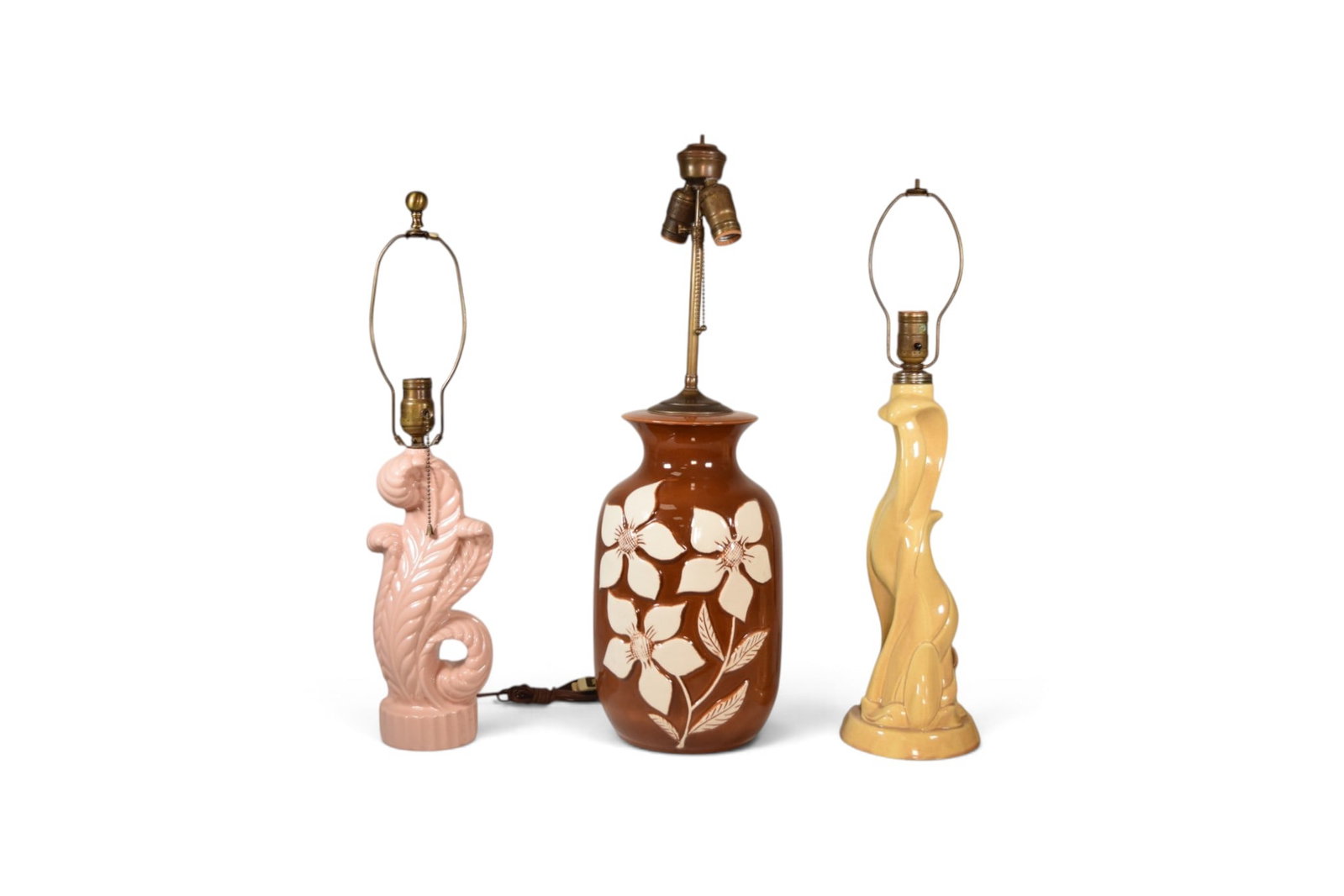 3 Mid-Century Pottery Table Lamps: Lot of 3 mid-century pottery lamps. Pink Haeger style leaf form lamp, yellow Haeger style lamp, brown pottery lamp with floral decoration. Brown lamp dimensions to top of cap: H: 25.5" W: 7.75" D: