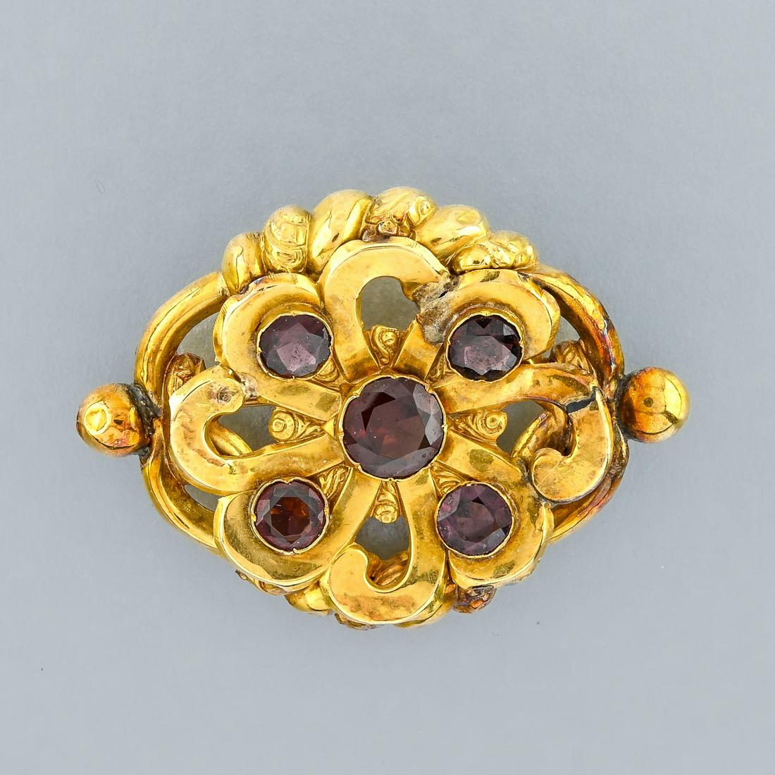 Brooch set with garnets: Brooch set with garnets 14 kt yellow gold. Hallmarks: none One repair, some dents. D : 3,2 cm Weight : 5,1 g