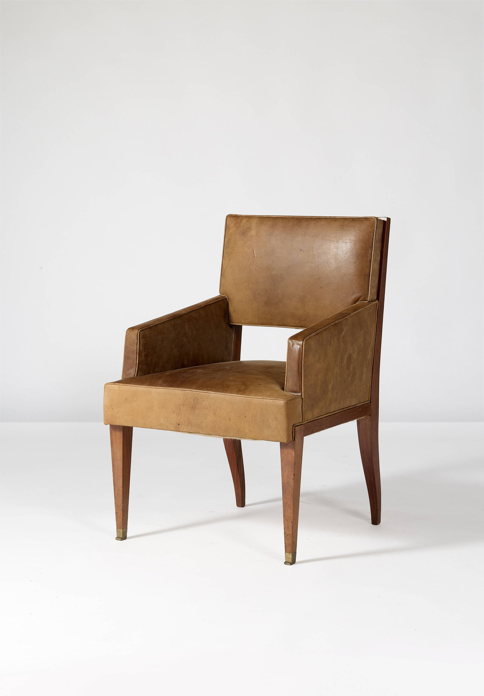 Jacques QUINET: Jacques QUINET Fauteuil – circa 1960 Structure en sipo, assise et dossier recouverts de similicuir et sabots antérieurs en bronze doré 89 × 62 × 62 cm Provenance : Commande