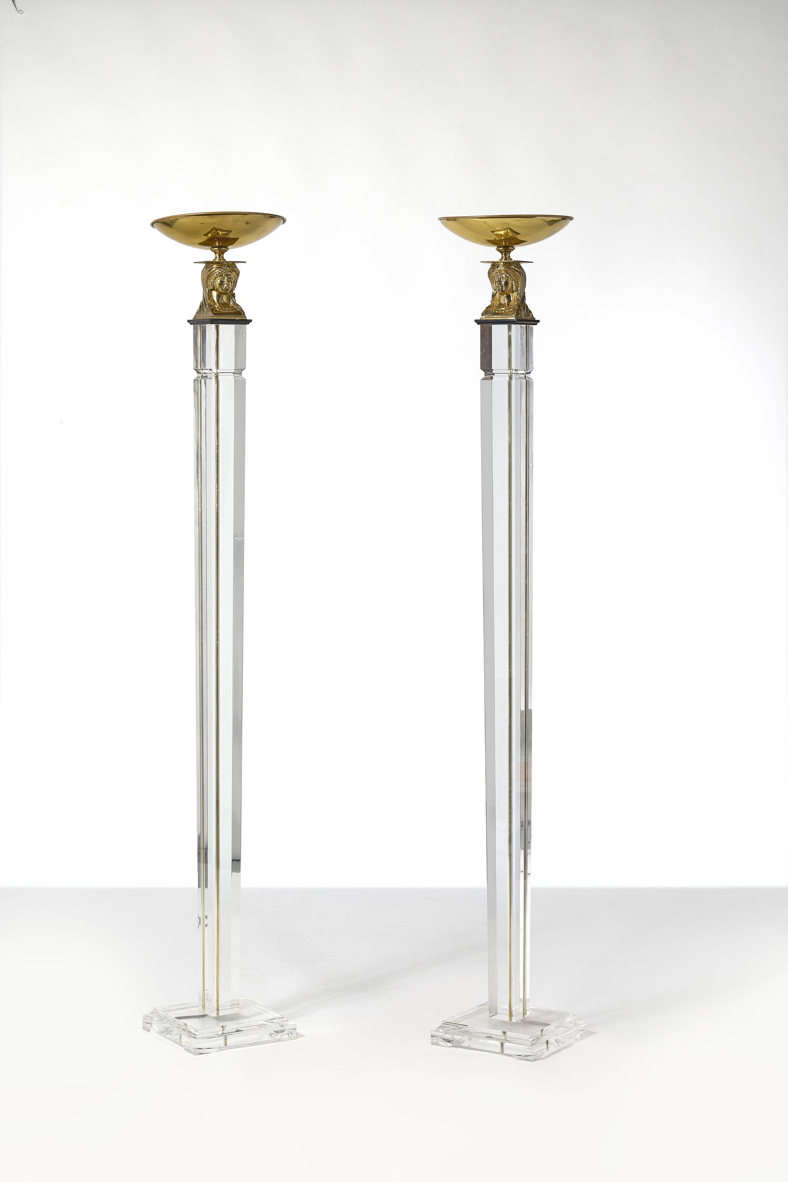 TRAVAIL FRANÇAIS: TRAVAIL FRANÇAIS Paire de lampadaires – circa 1970 Fût et base en méthacrylate, diffuseur en laiton doré supportés par des têtes de femmes 189 × 31 cm A pair o