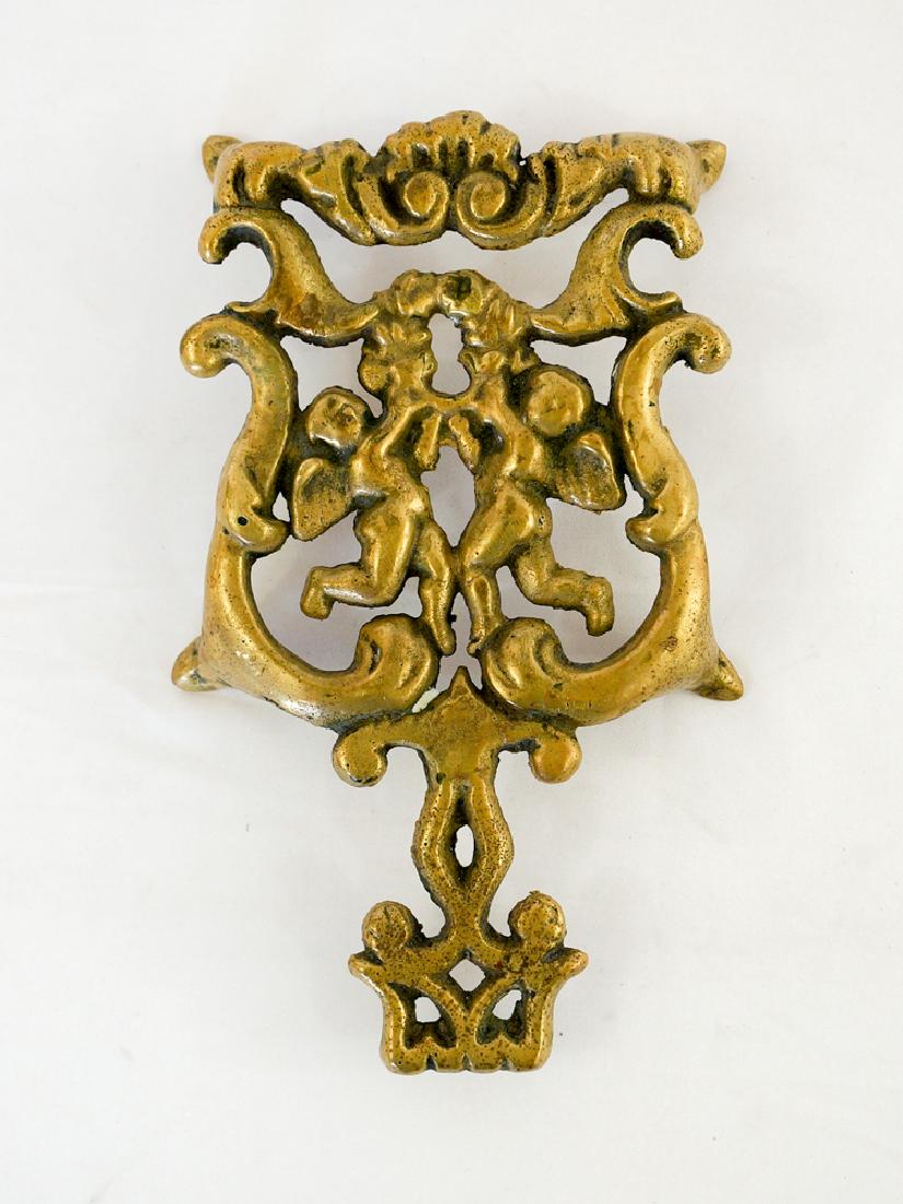 An Antique Brass Trivet with Angels: An antique brass trivet with angels. Measures 1" x 8" x 4.75". We ship most items in house. Exclusions include furniture, oversized framed artwork and heavier items. Please inquire for shipping quotes