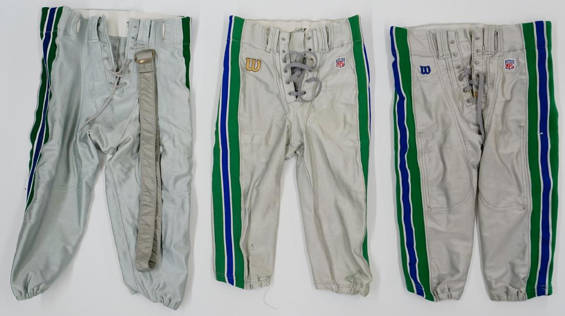 Three Pairs Seattle Seahawks Pants: Three pairs of Seattle Seahawks Professional Model pants. One pair has handwritten in black marker "89P", another "73P" and the third "P". Includes one belt. We ship all items from this auction in-hou