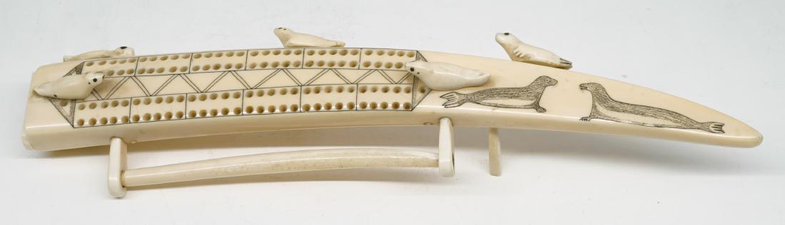 Alaskan Scrimshaw Cribbage Board: Alaskan scrimshaw cribbage board. Measures 13.75 in. in length. One leg not attached but included. Provenance: from the estate of war hero and former Montana state representative Butch Wadill. We ship
