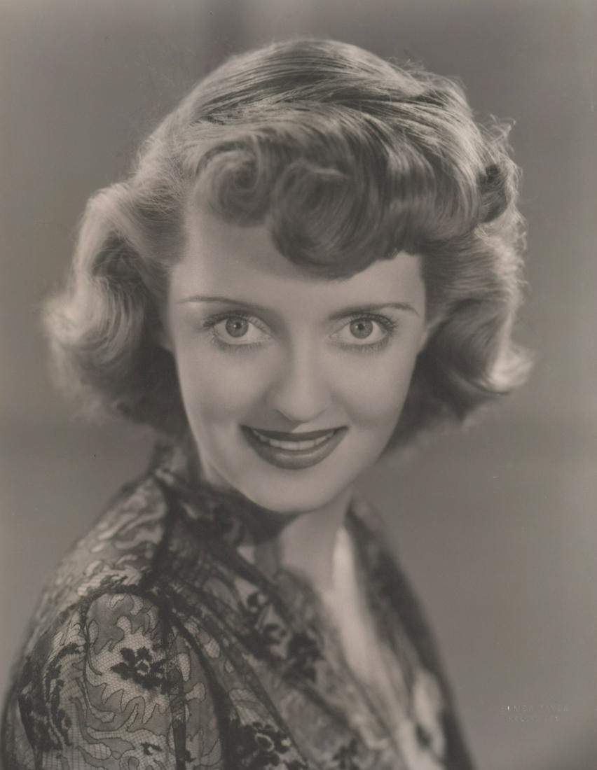 Bette Davis Photographed by Elmer Fryer: Bette Davis oversized publicity still circa 1930's/40's. Photographed by Elmer Fryer with photographers blind stamp lower right. Matt surface, double-weight black and white gelatin silver print. Measu