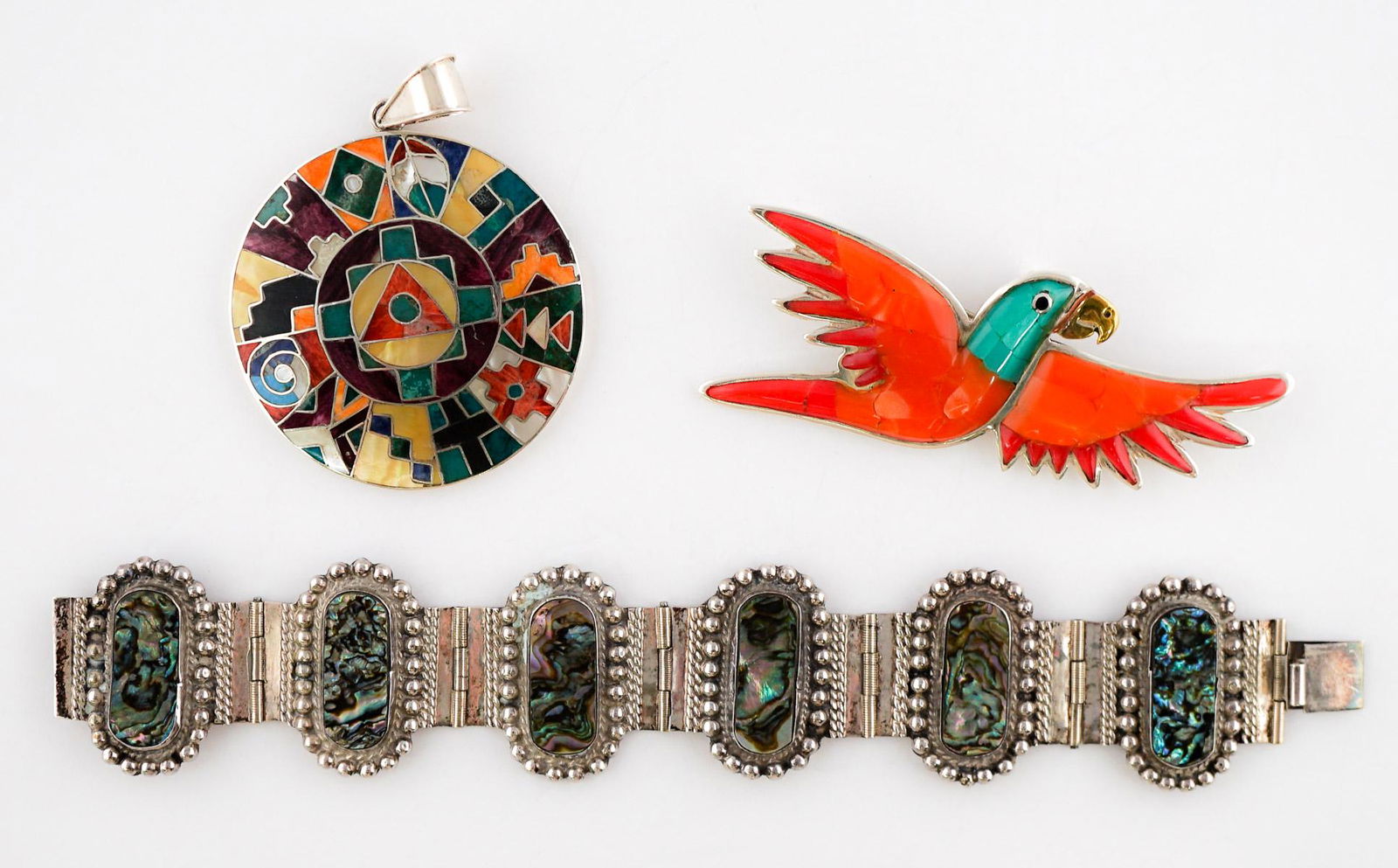 Mexican Sterling and Multi-Stone Jewelry: Group of sterling and multi-stone jewelry from Mexico. Includes round multi-stone inlaid pendant measuring 2 in. diameter, sterling and abalone bracelet measuring 7 in. x 1.25 in. and inlaid, multi-st