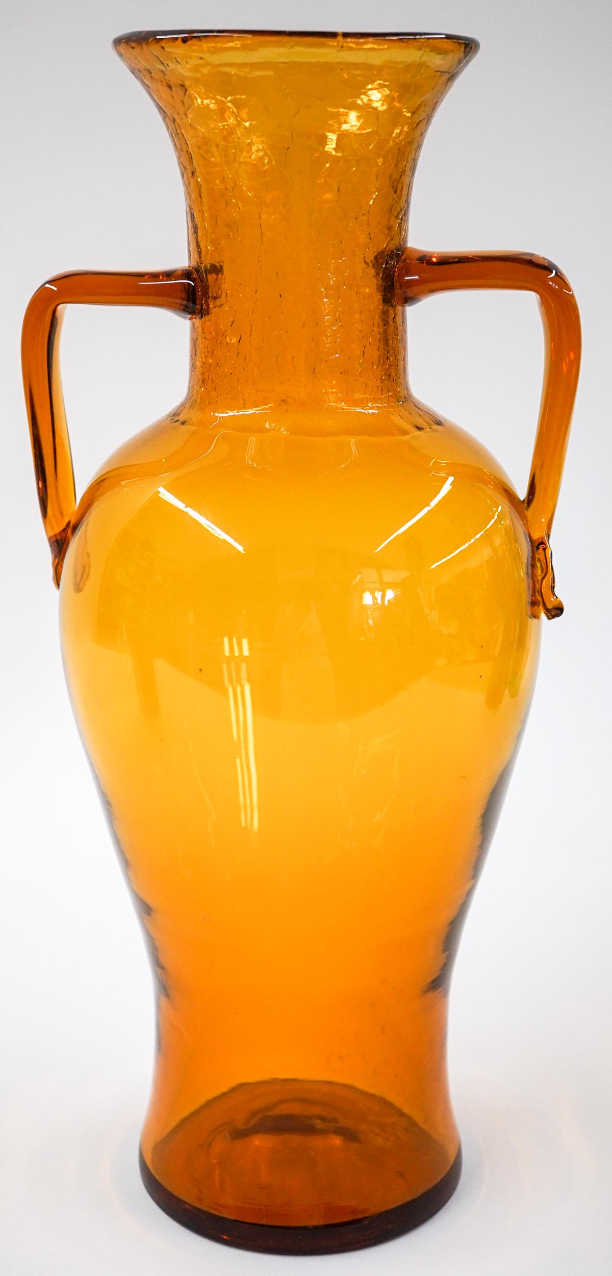[Blenko] Mid-Century Large Amber Glass Vase: Blenko (or other maker) mid-century amber glass handled large vase. Measures at base 4 in. diameter and 7 in. wide at handles with a total height of 14.5 in. No chips, cracks or repairs. Provenance: T
