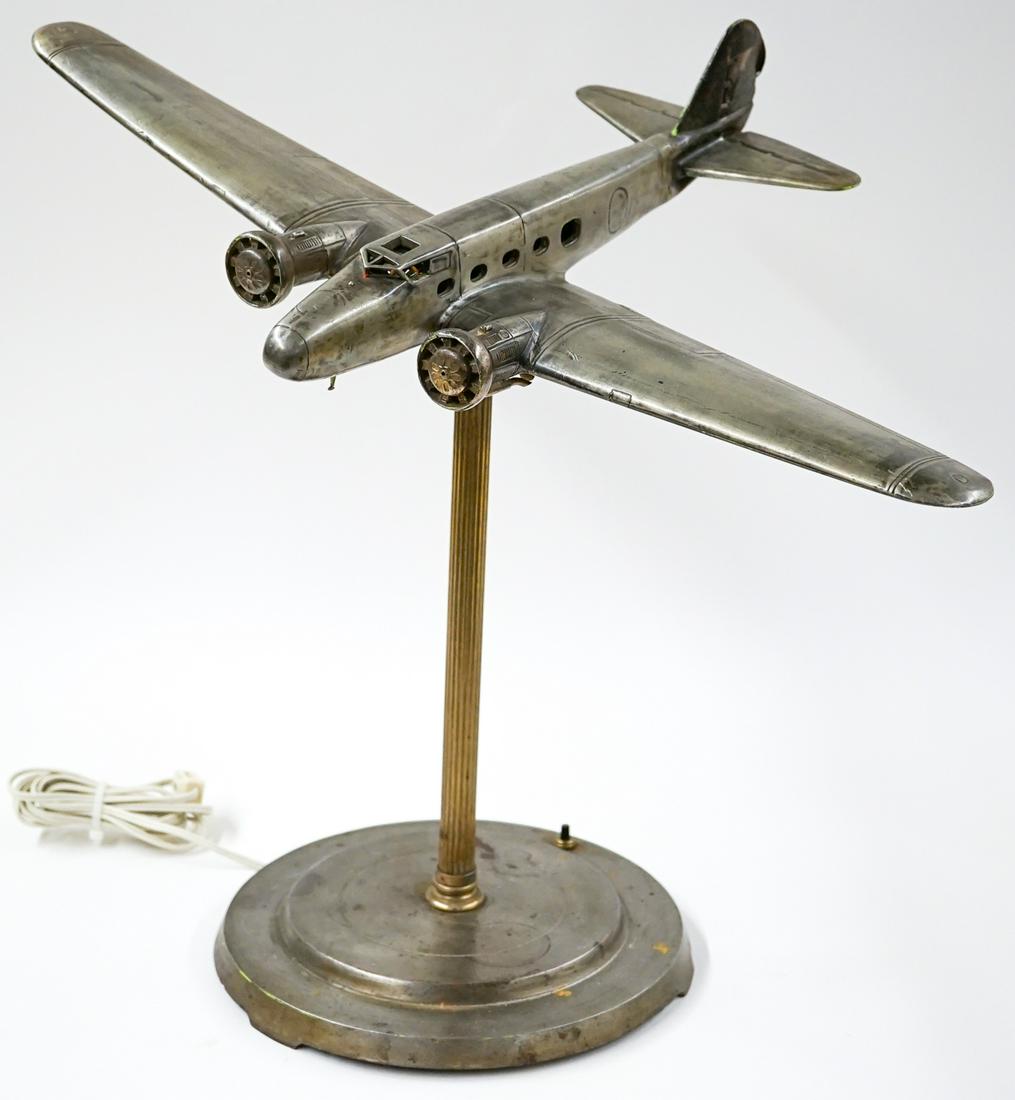 Vintage Airplane Light Fixture: Vintage metal airplane light fixture with married base. Measures from base to socket 14 in. The diameter of the base is 10 in. Tested. The plane's wing span is 22 in. If lot is absent of a condition r