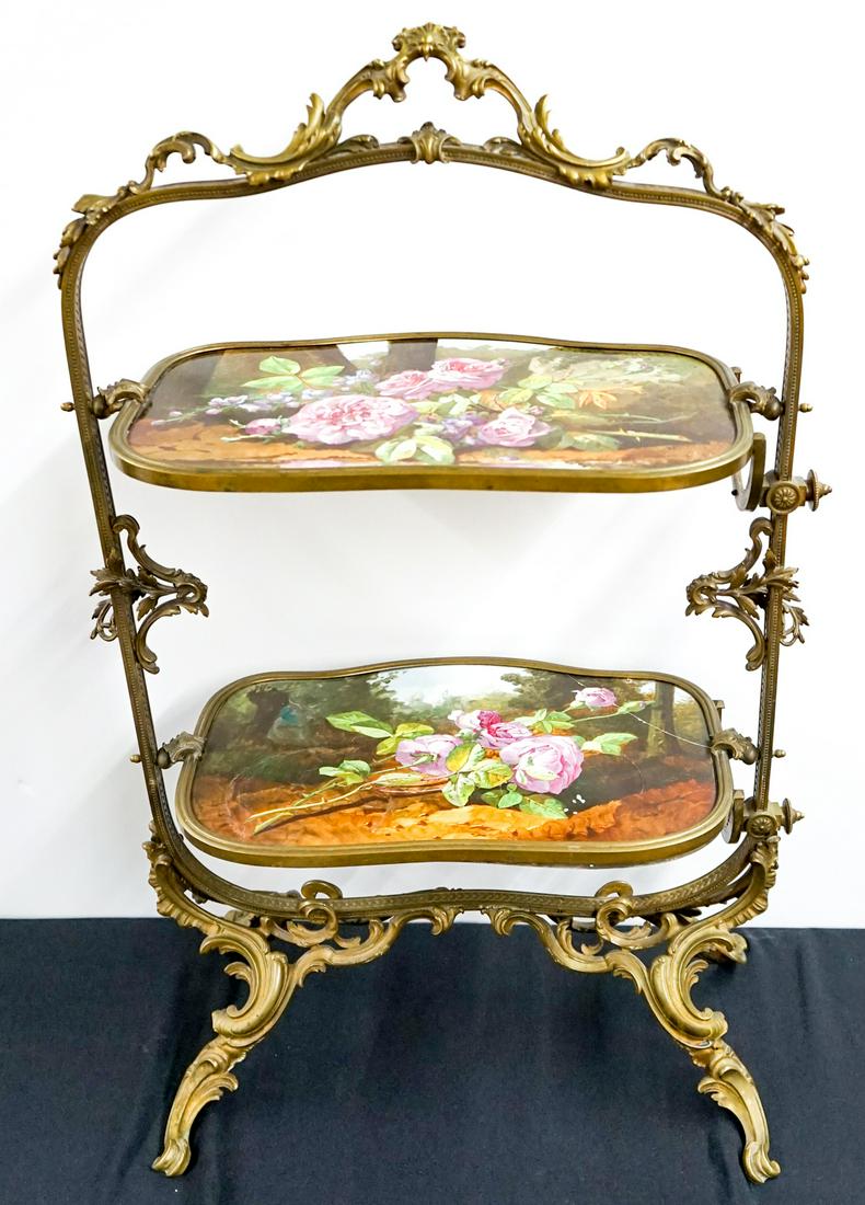 Porcelain / Metal Two-Tier Display Stand: Vintage gilded metal display stand with two-tier porcelain inserts. Floral design. Both shelf's tilt upright, lower shelf knob is to tight to release. The lower shelf is cracked and needs to be reseat