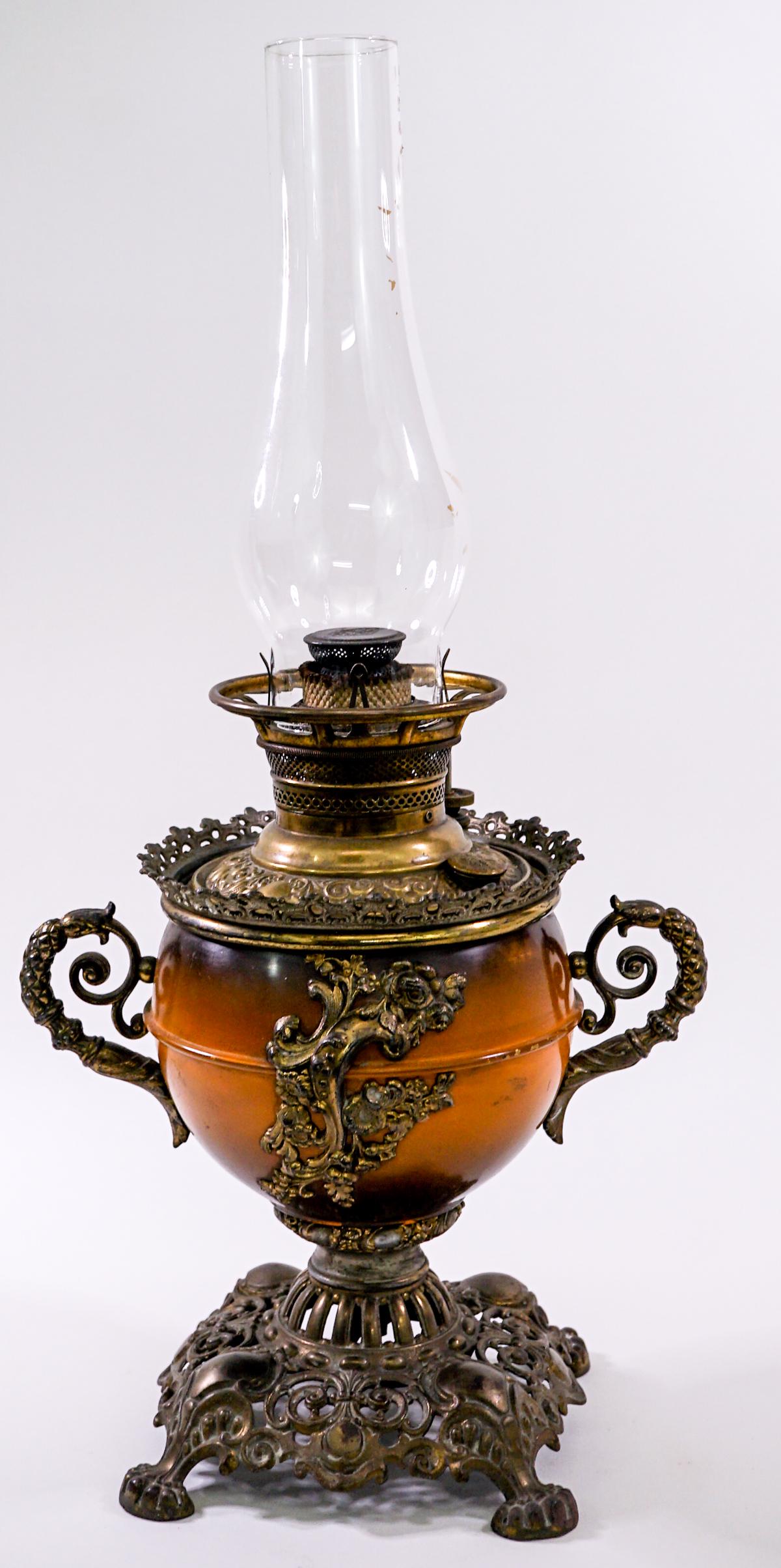 Vintage Ornate Oil Lamp: Vintage ornate oil lamp. Measures 6.75 in. square at base x 13 in. to top of lamp base and 22 in. total height to top of hurricane x 12 in. wide. Weighs 5 lbs 12 oz. If lot is absent of a condition re