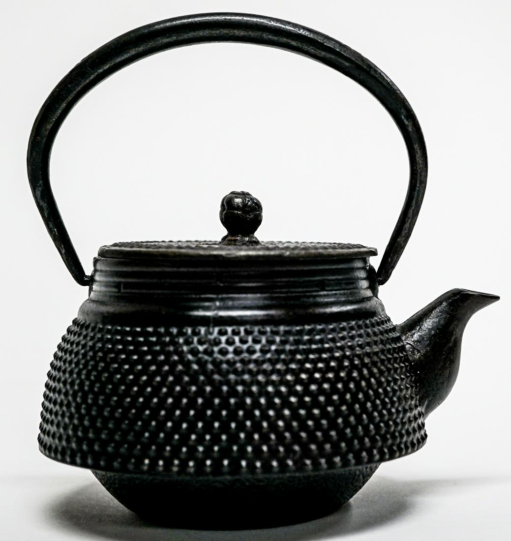 Small Japanese Tetsubin Cast Iron Teapot: Small antique Japanese tetsubin cast iron teapot with raised dots. Character marks near spout. Measures 5.25 in. to top of handle x 4.5 in. wide x 3.75 in. across base. Weighs 1 lb 1 oz. If lot is abs