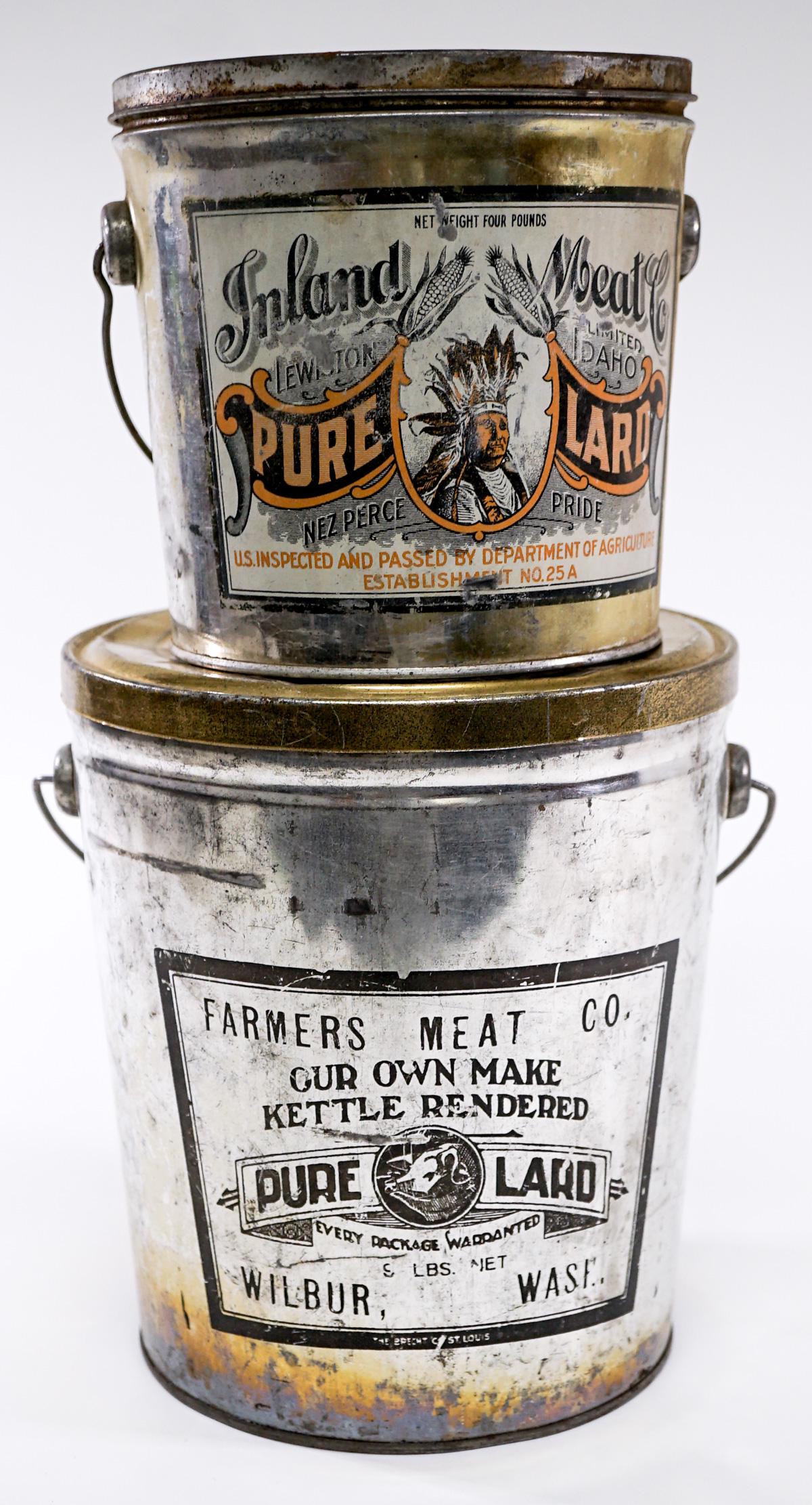 Vintage Lard (2) Tins [Inland Meat Co. Nez Perce]: Two (2) vintage lard tins. Includes: Inland Meat Co. Lewiston, Idaho 'Nez Perce Pride'; and Farmers Meat Co. Wilbur, Washington. Measure 6 in. - 8.5 in. tall. If lot is absent of a condition report on