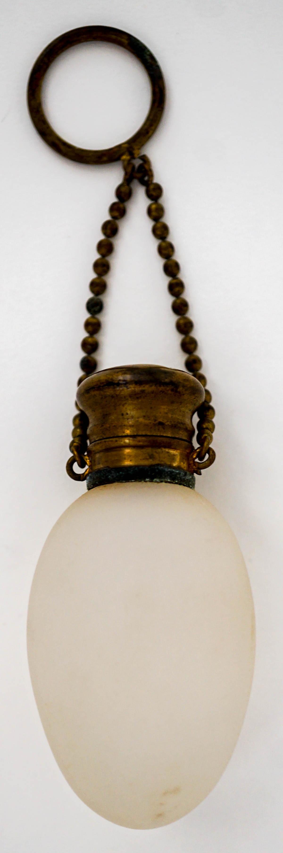 White Satin Glass Egg Shape Scent Bottle: Measures 2.75 inches x 1.25 inches. Hinged-top with stopper, chain and finger ring. No damage. Provenance: Previously Sabra Carter collection. Collected 1950's-1970's. then by family descent to the Ma