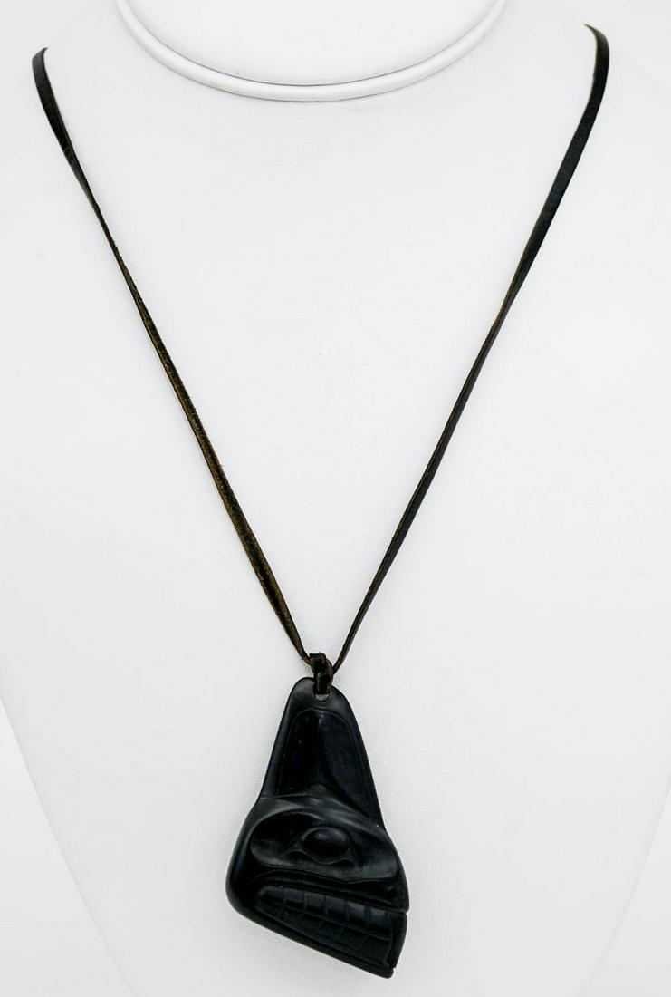 Argillite Pendant Pacific Northcoast [Haida]: Carved argillite pendant signed by artist S. Collinson and dated '75 on underside. Measures 2 in. x 1.5 in. Black twine necklace. If lot is absent of a condition report one may be requested via email.