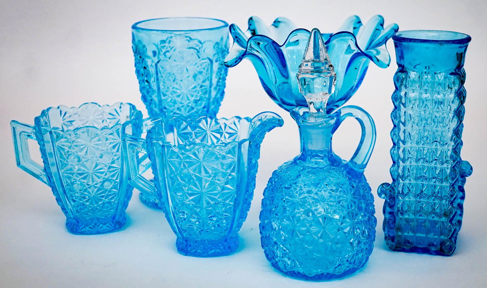 Vintage Blue Glass (6) Pieces [Daisy Pattern]: Six (6) vintage glass pieces. Includes" 1) Aqua blue daisy pattern creamer (4 in. tall), sugar (3.5 in. tall), cruet with stopper (6.75 in. tall) and goblet (6 in. tall). No chips. 2) Blue vase (6.125