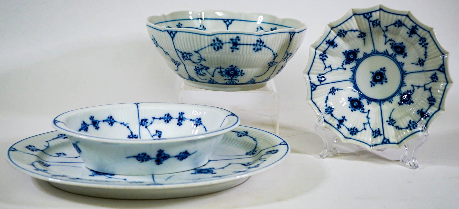 Royal Copenhagen (4) Blue Serveware: (4) four pieces of fluted Royal Copenhagen serveware. Includes: open vegetable dish 306 measures 8 in. x 6.25 in. x 2 in. tall; fluted bowl 141 measures 6.5in. across rim x 1.625 in. tall; round bowl