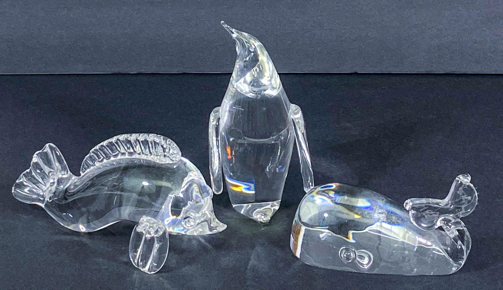 Steuben Crystal (3) Figural Whale, Penguin, Fish: Three (3) Steuben crystal glass figurines. Includes: Whale measures 5 in. long; penguin measures 6 in. tall, and fish measures 7 in. long. Very minor chip at top of nose of whale. Feels rough, very ha