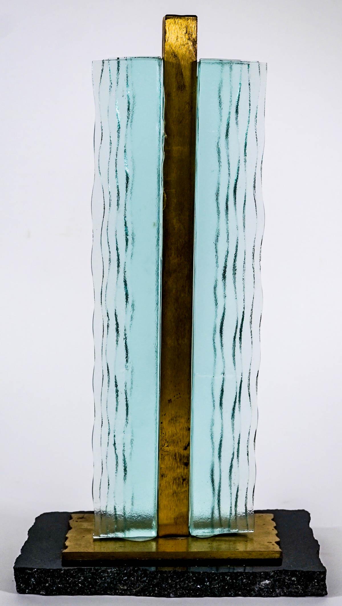 Sculpture of Glass, Metal and Stone: Sculpture of layered green textured glass, metal accents with a stone base. Measures 17 in. tall and the base measures 9.5 in. x 5.5 in. Weighs 16 lbs. Provenance: Estate of David Milot. David was a R