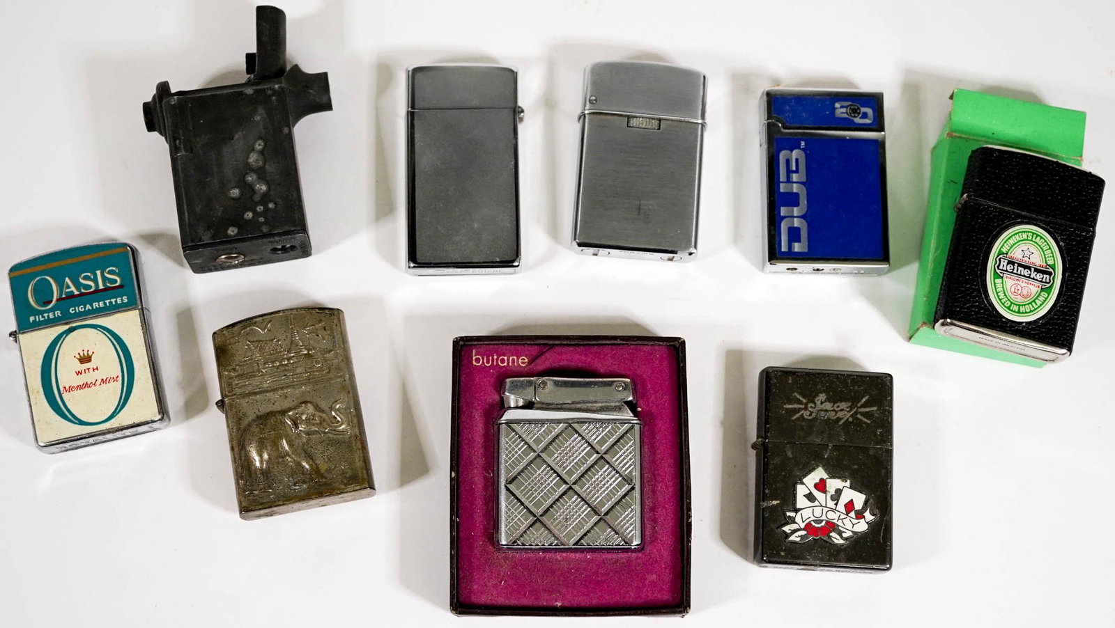Nine (9) Vintage Lighters [Heineken]: Nine (9) vintage lighters. Advertising and other. Note the Heineken is with original green box and appears unused all others are used condition with no evidence of damage or repair.. If lot is absent 