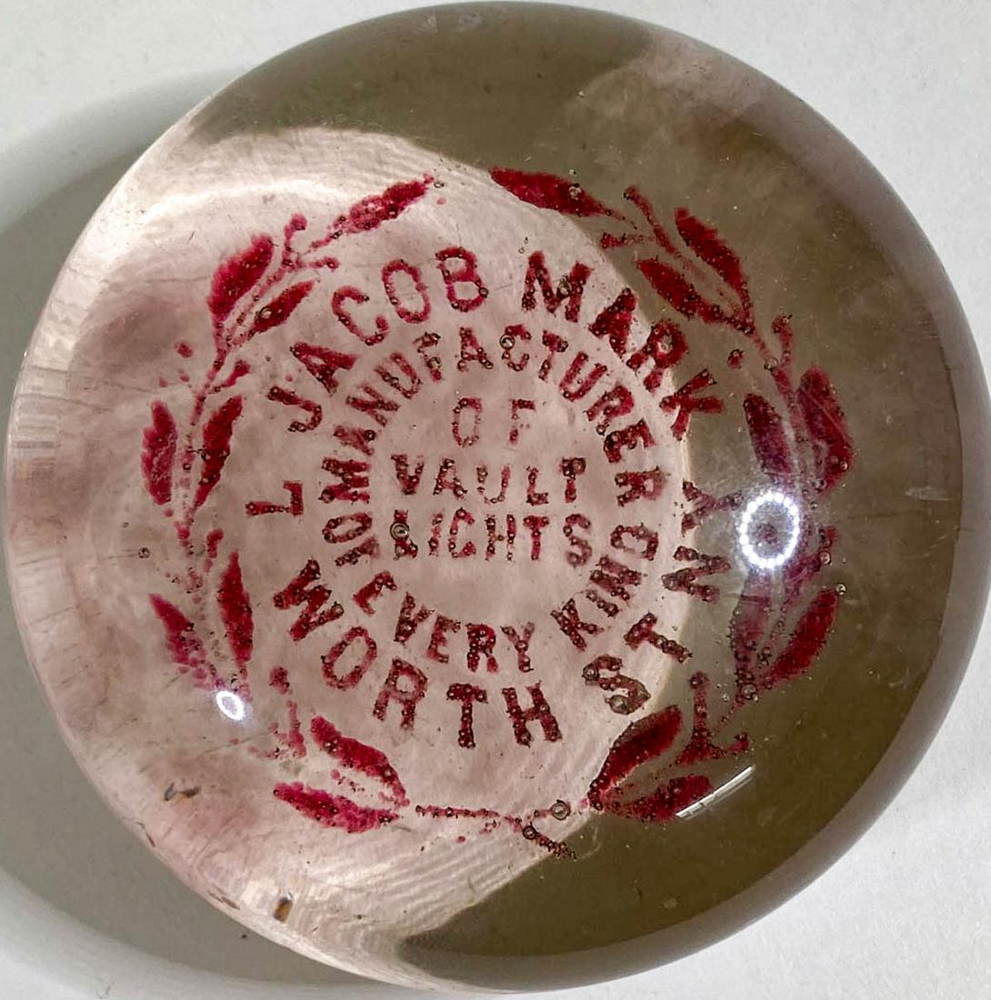 Jacob Mark Vault Lights Paperweight: [New York, New York] Jacob Mark Vault Lights Antique Glass Advertising Paperweight (red letters). Measures 1.75 x 3.25 inches. Very good condition with surface scuffing and light scratches on edges of