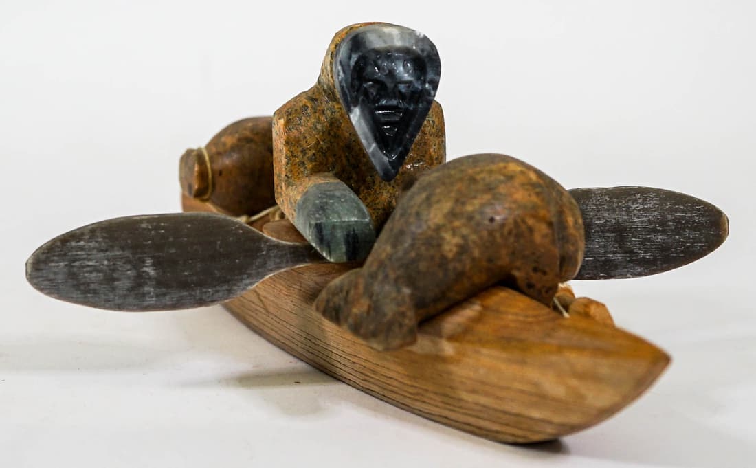Glenn Tootkaylok Kayaker Canoe w/Soapstone Figure: Alaskan wood canoe sculpture with soapstone figures signed 'Glenn Tootkaylok' and dated Nome, Alaska '96. Measures 9 in. long. No evidence of damage or repairs. Provenance: Private Collection. If lot