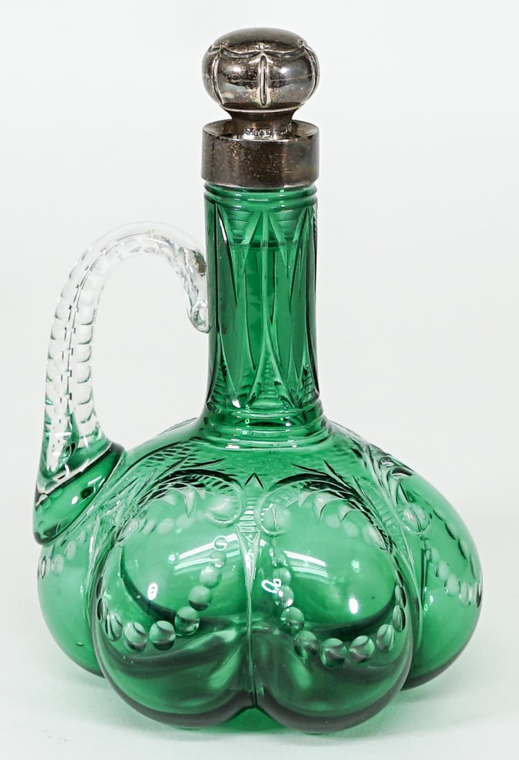 John Grinsell and Sons Bottle w/ Sterling Topper: John Grinsell and Sons green cut glass handled bottle with sterling mounted stopper. Measures 5.5 in. tall x 3.5 in. wide. No evident cracks or repairs. If lot is absent of a condition report one may 