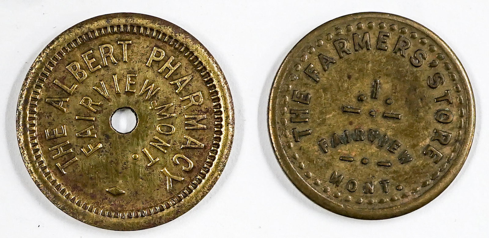 Two Fairview, Montana Trade Tokens: Fairview, Montana The Albert Pharmacy (round token, 20 mm, VG-EX/EX, Good For 5c In Trade) and Fairview, Montana The Farmers Store (round, 20 mm, excellent condition, Good For 5c In Merchandise). If l
