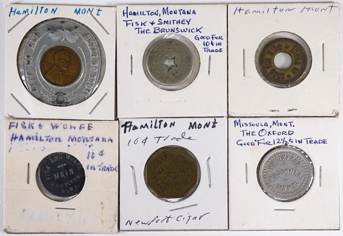 Montana (6) Trade Tokens [Hamilton, Missoula]: Six (6) Montana trade tokens. Lot measures 2 in. H x 2 in. W x .75 in. D. The absence of a condition report does not imply that the lot is in perfect condition or completely free from wear and tear, i