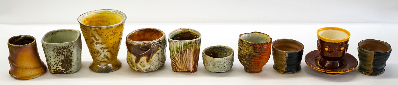 Josh DeWeese and Others (10) Studio Pottery Cups: Ten (10) Josh DeWeese, R. Smith, Alexandria Crow, Richard Smith and others pottery cups. Note one (1) includes saucer. Measure 1.5 in. to 4.25 in. tall. No evident cracks or repairs. Provenance: Estat