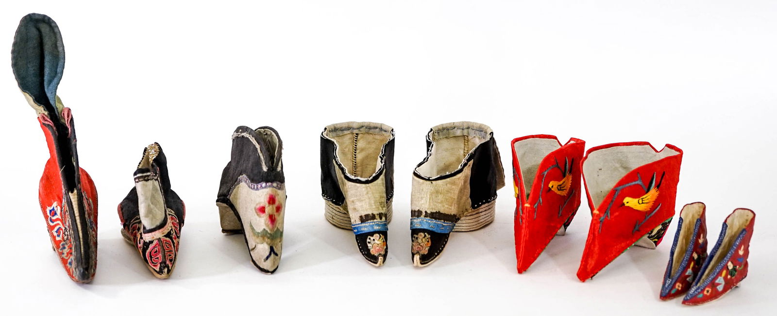 Antique / Vintage Chinese Lotus Shoes Embroidered: Seven (7) Embroidered Lotus shoes and a small decorative ceramic pair. Includes: 2 pair embroidered shoes measure 4.5 and 5.5 in. long x 1 and 2 in. across sole; three embroidered single shoes non-mat