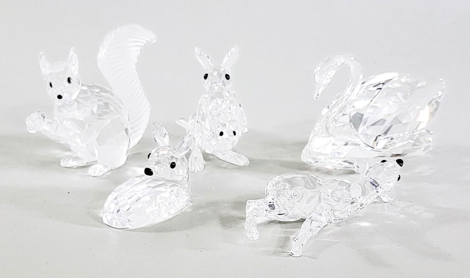 Five Swarovski Crystal Figures: 1. Fawn 2. 10 Anniversary Squirrel 3. Kangaroo with Pouch Baby 4. Swan and 5.Lying Doe No Damage with original boxes. Measures 9 x 9 x 8 in. for shipping purposes only (box size). The absence of a con