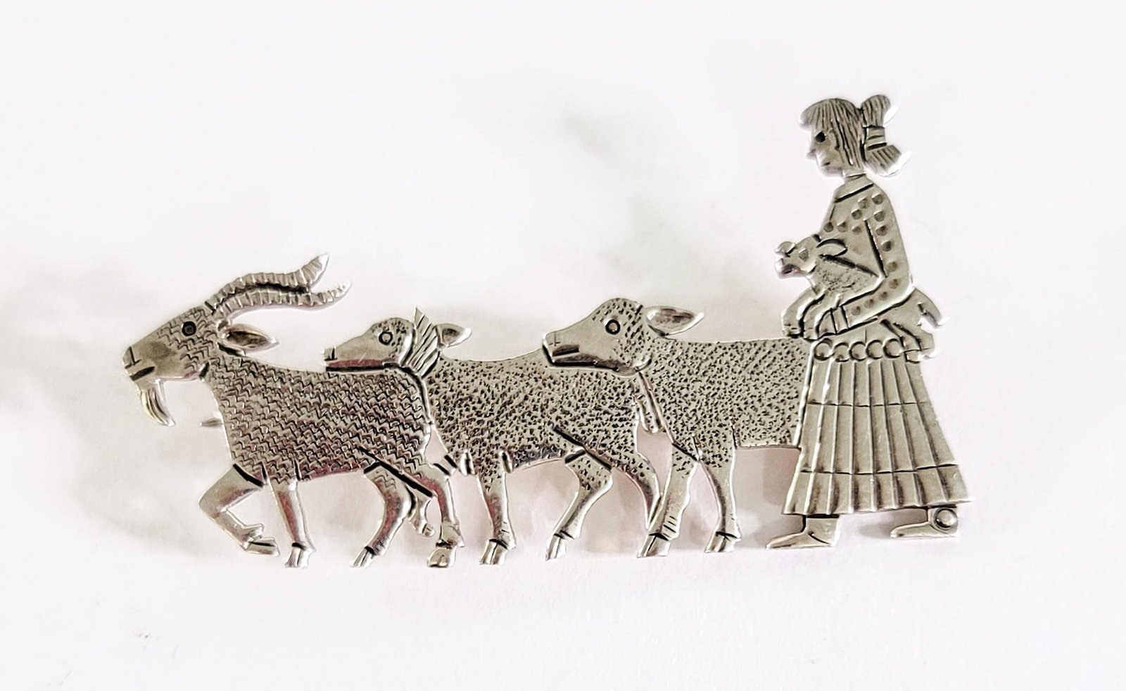 Clarence Lee / Russell Lee Sterling Brooch: Navajo Clarence Lee / Russell Lee Sterling 'Girl with Animals' measures 1.25 x 2.5 in. Weighs 10 grams. Lot measures 1.5 in. H x 2.5 in. W x 625 in. D for shipping purposes only. The absence of a cond