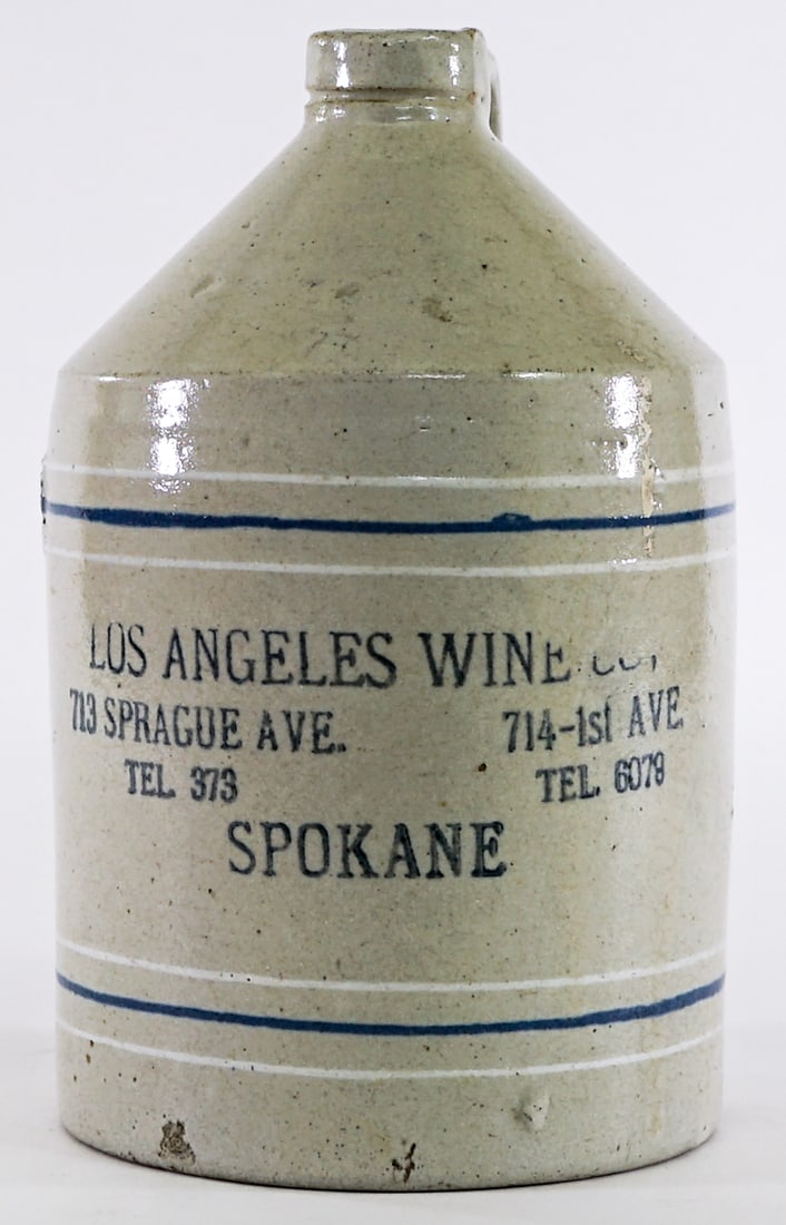 Los Angeles Wine Co. Crock Jug Spokane WA: Measures 8.75 in. tall x 5.25 in. diameter. Chips to bottom edge; crack to handle. Lot measures 8.75 in. H x 5.25 in. W x 5.25 in. D for shipping purposes only. The absence of a condition report does