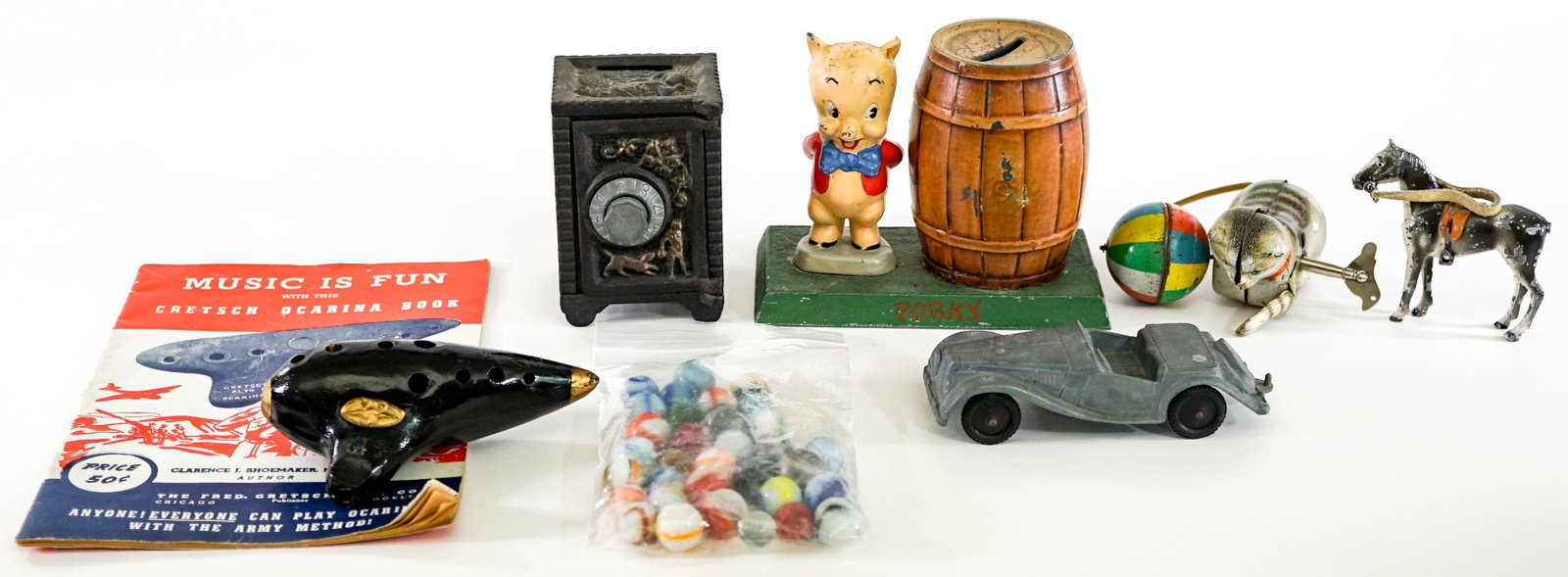 Group of Small Vintage Toys [Mixed Condition]: Includes: Porky Pig Coin Bank ; Safe Coin Bank; Windup cat and ball; bag of marbles and more. Lot measures 6 in. H x 10 in. W x 8 in. D for shipping purposes only. The absence of a condition report do