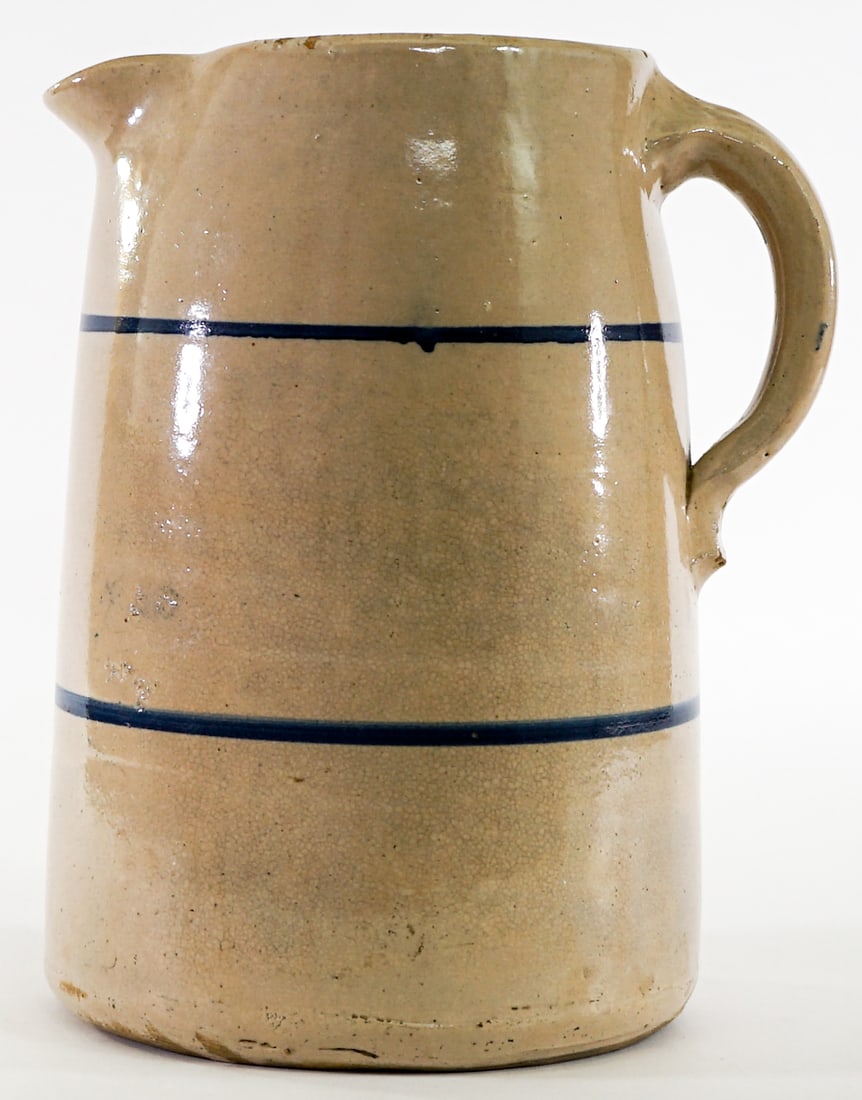 Cream Glazed Blue Band 9.5IN Stoneware Pitcher: Cream Glazed Blue Band Stoneware Pitcher measures 9.5 in. tall x 8 in. x 6 in. Chips at rim. Lot measures 9.5 in. H x 8 in. W x 6 in. D for shipping purposes only. The absence of a condition report