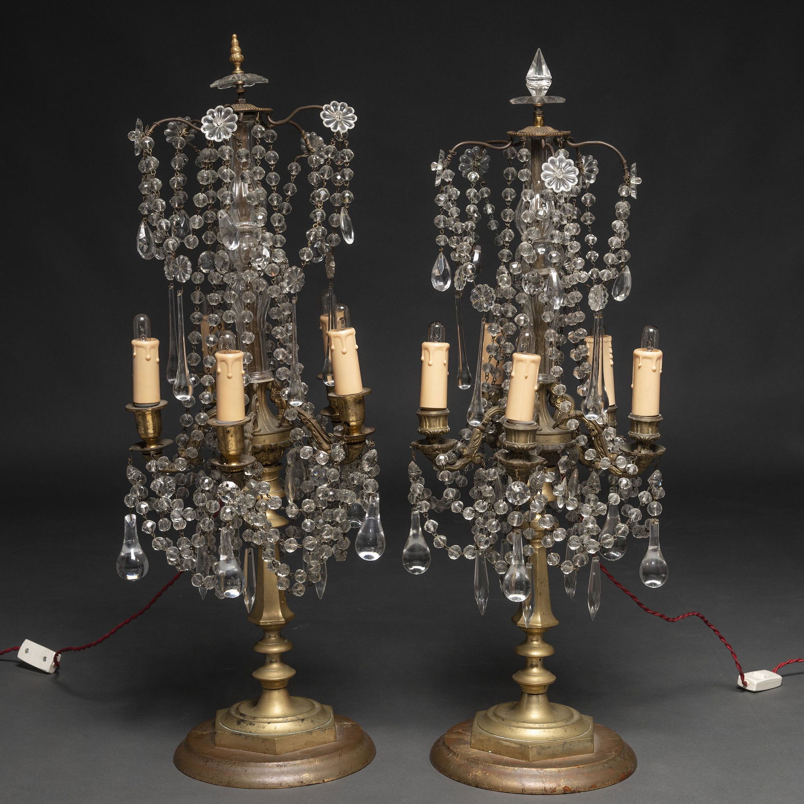 Pareja de Girándoles de cinco luces en cristal y: Presentan colgaduras en cristal con rosetones y lágrimas de gota. Apoyan sobre base de madera. Incorporan instalación eléctrica. Medidas: 72 x 22 cms. Disciplina: Artes Decorativa