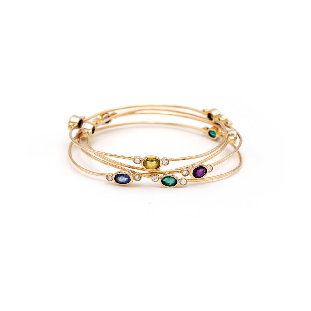 Four 18kt yellow gold cuff bracelets: , weight 27 g., embellished with emeralds, blue, pink and yellow oval-cut briolet sapphires circa 5 ct alternating with brilliant-cut diamonds circa 1 ct, diameter 6.5 cm.