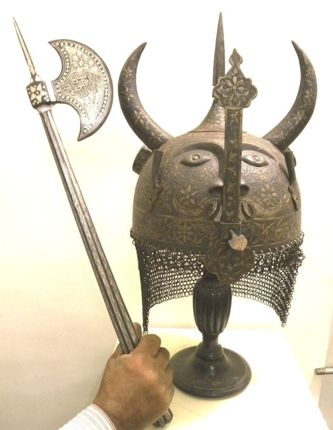 STUNNING RARE HELMET DEMON DEVIL FACE TWO HORNS & SILVER AXE FOLDING ARABIC INSCRIPTION: A rare finding of set of helmet and AXE, Made of hand forged steel, hand hammered and chiseled. Skull : Demon Devil face with two horns chiseled & mustache & beard, this make the helmet collection pie