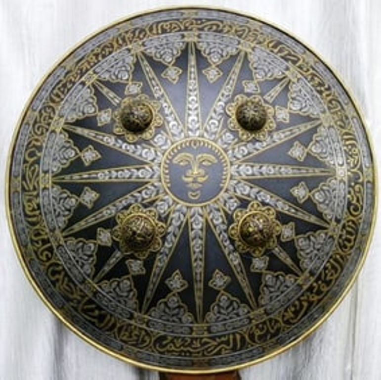 INCREDIBLE SUNBURST SHIELD SUN FIG. RAYS & ARABIC CALLIGRAPHY LARGE FINELY CARVED SPIRALING SEGMEN: This exquisite circular metal shield showcases a majestic sun face at its center, symbolizing power, warmth, and protection. Radiating sun rays extend outward in perfect symmetry, surrounded by finely