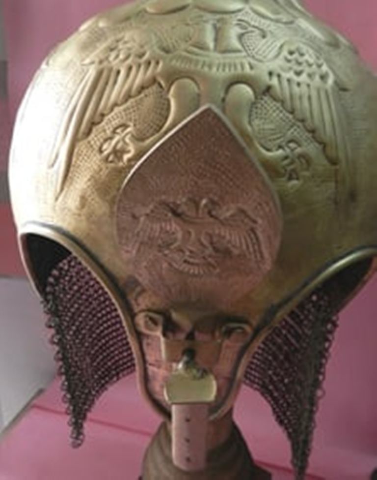 ANICENT BRASS METAL HELMET WITH DOUBLE HEADED EAGLE MOTIFS SYMBOLIZING POWER STRENGTH: his image showcases an intricately crafted helmet or domed crown, featuring finely embossed double-headed eagle designs symbolizing power, authority. . The surface displays delicate engraved patterns 