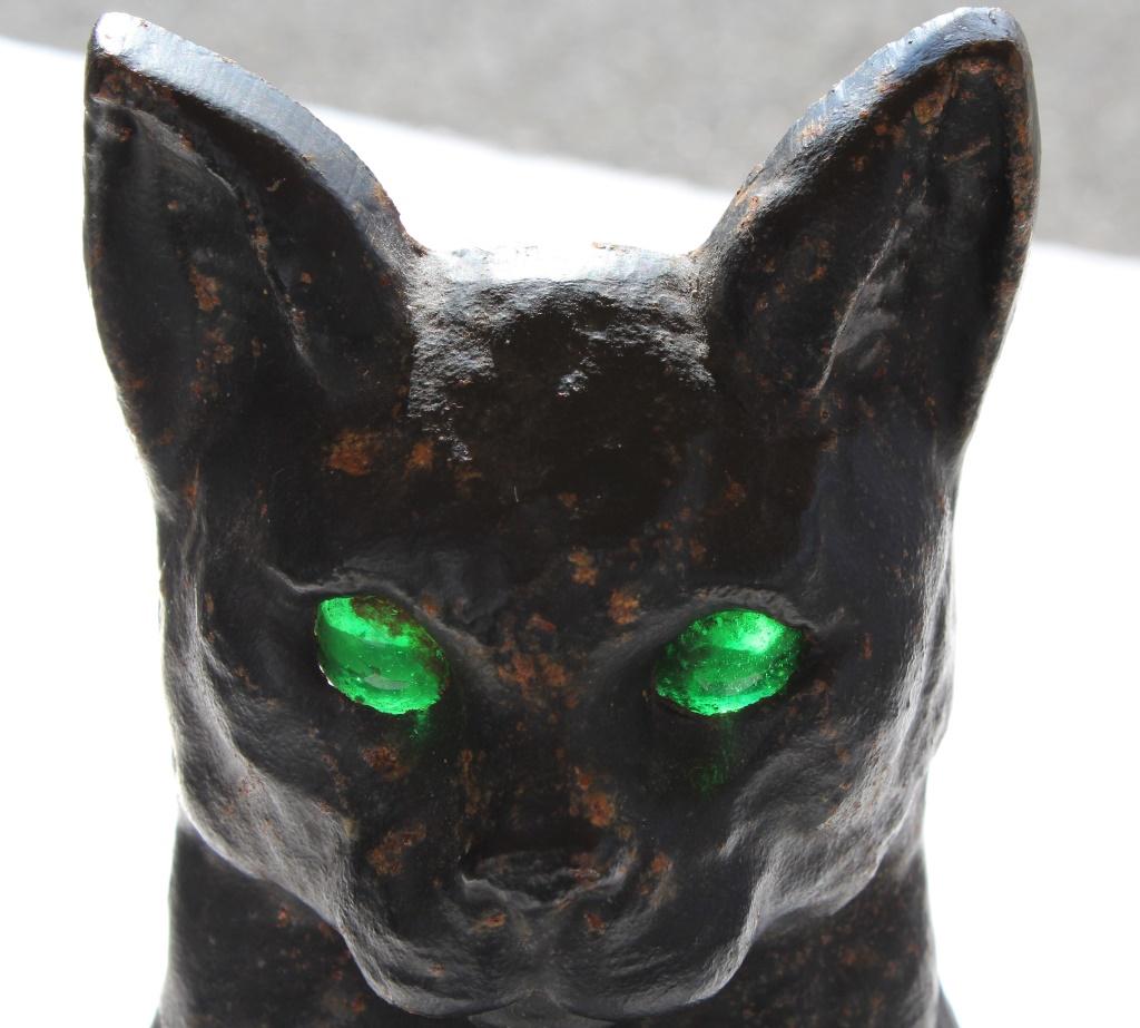 Iron Cat Andirons with Green eyes: Glowing Green cat's eyes andirons. Cat log holders with green eyes that glow with the flame. Title: Glowing Green cats eyes andirons. Medium: Iron. Size: 17 X 17 X 7 in. Signature: Unsigned. Unframed.