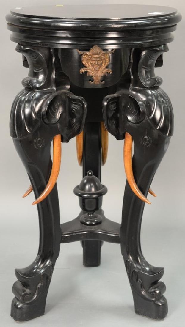 Ebonized table/pedestal with revolving top on carved: Ebonized table/pedestal with revolving top on carved elephant supports with faux tusks of wood. ht. 33in., dia. 18 1/2in.