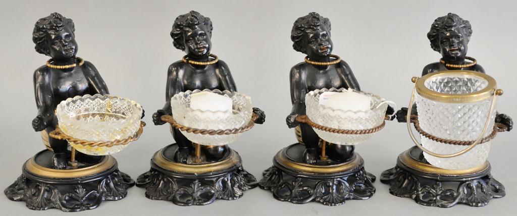 Set of four polychrome cast metal blackamoor: Set of four polychrome cast metal blackamoor candlesticks having kneeling figure supporting a ring and a glass vessel. ht. 6 1/2 in.