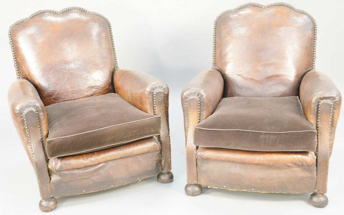 Pair of leather upholstered arm chairs with brass tacks: Pair of leather upholstered arm chairs with brass tacks and cloth cushions, (seat corners of leather is seperated). ht. 35 1/2 in., wd. 32 in. Provenance: Former home of Mel Gibson, Old Mill Rd, Green