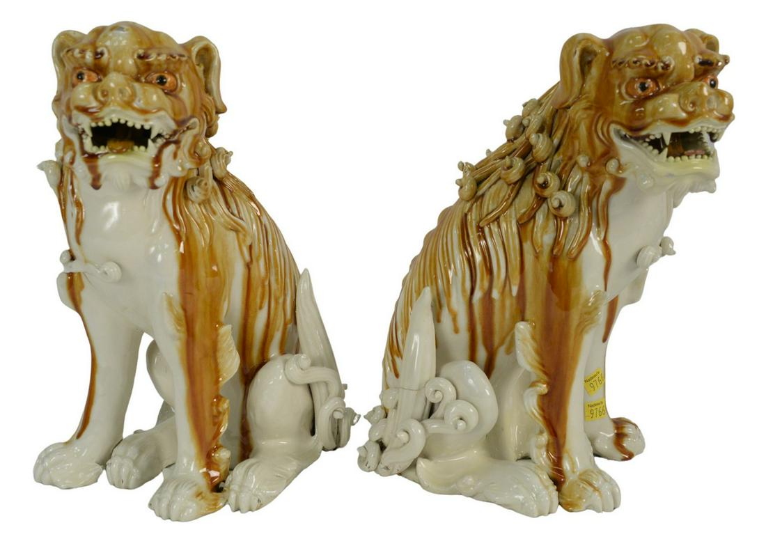 Pair of Porcelain Foo Dogs in a white and brown glaze,: Pair of Porcelain Foo Dogs in a white and brown glaze, height 14 inches (having several chips and repairs).